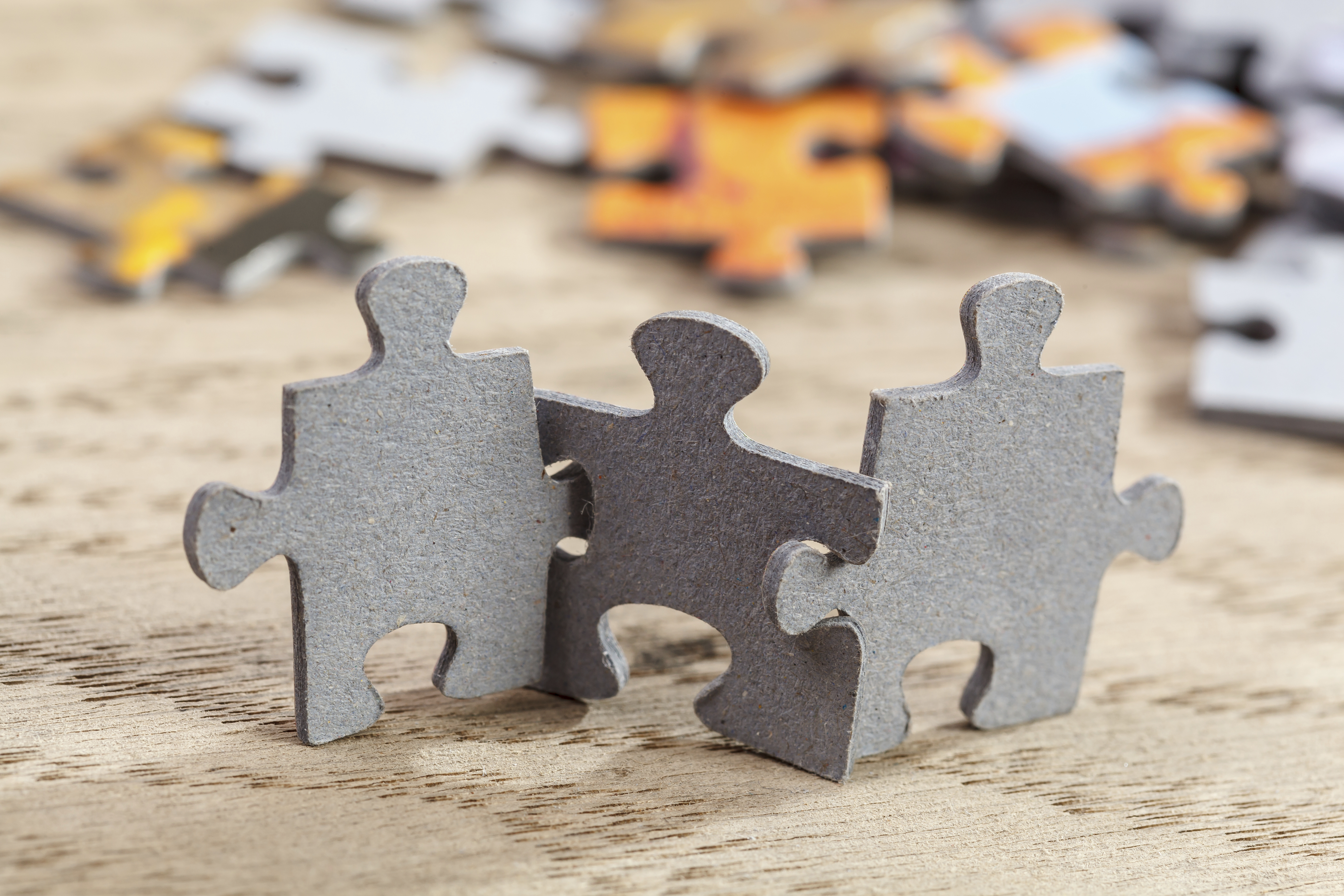 Concept of teamwork: Three jigsaw puzzle pieces on a table joint together. Shallow depth of field